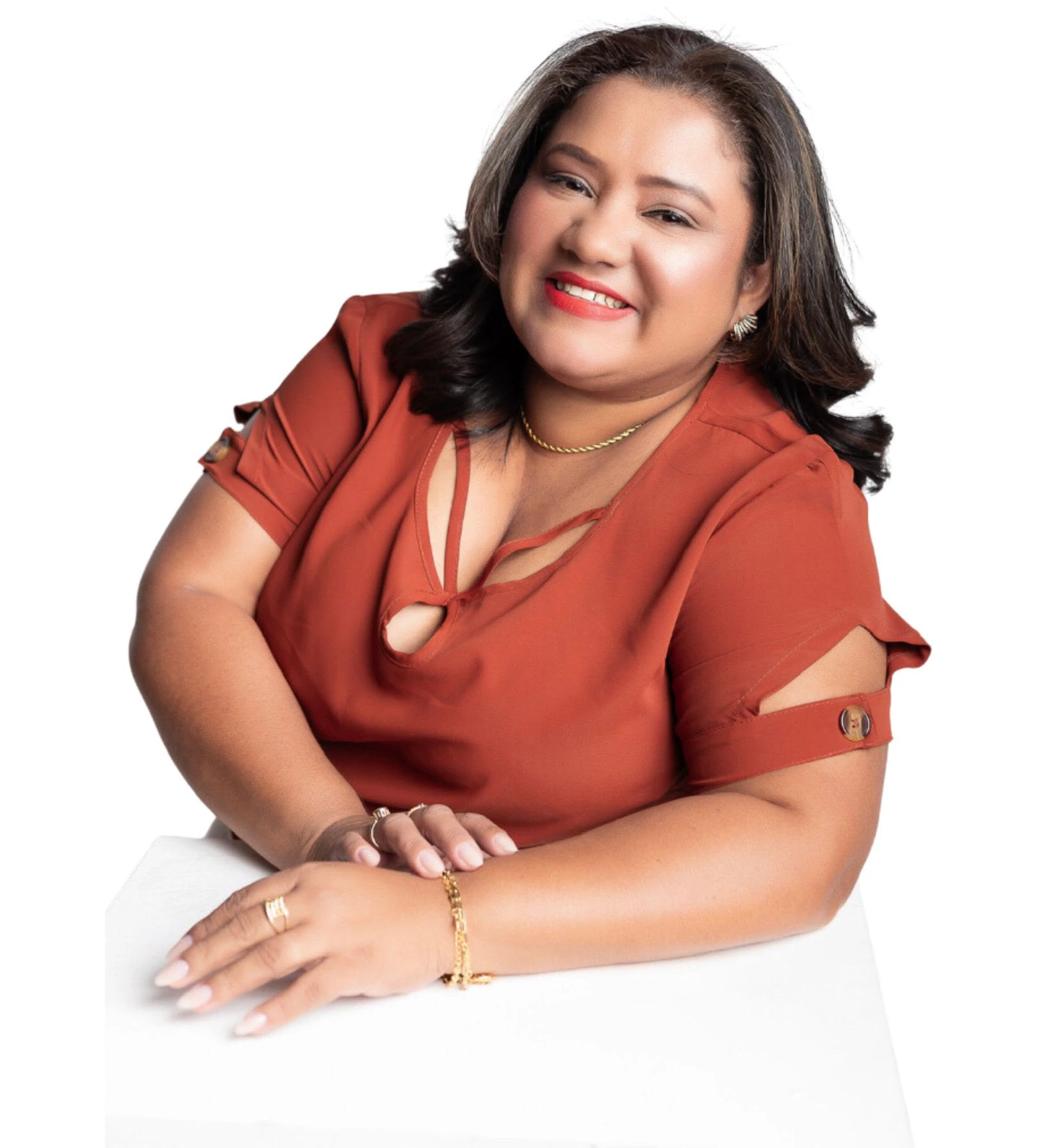 Rose Braga a sorrir, de blusa terracota, com as mãos apoiadas numa mesa branca